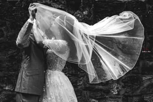 Brautpaar küssend vor einer Mauer