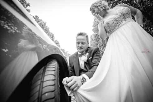 Bräutigam putzt mit dem Brautkleid das Auto