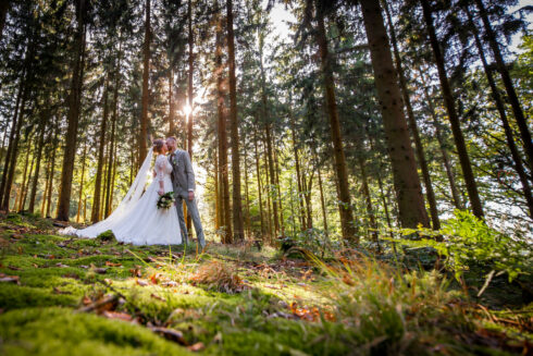 Brautpaar im Wald mit romantischer Herbstsonne im Hintergrund