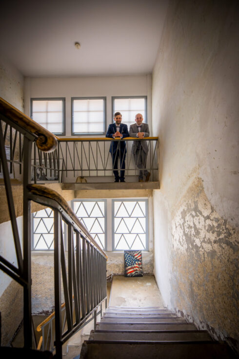 Hochzeitspaar steht auf einer Treppe in einem alten Industriegbäude